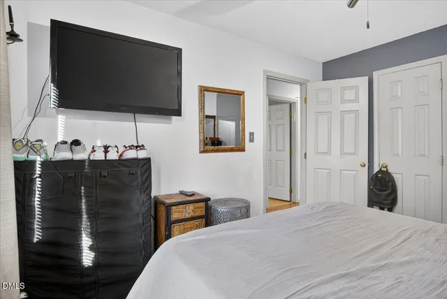 a bedroom with a bed and a flat tv screen on dresser