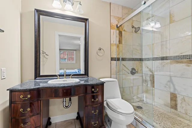 a bathroom with a sink a toilet a mirror and shower