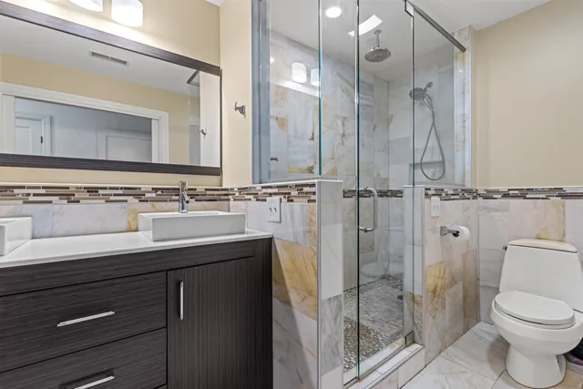 a bathroom with a sink a toilet a mirror and shower