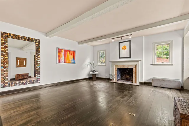 a view of an empty room with wooden floor fireplace and a window