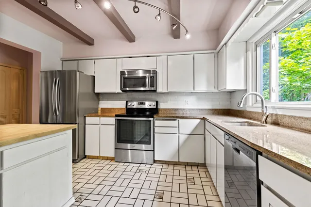 a kitchen with stainless steel appliances granite countertop a refrigerator a sink a stove a microwave and cabinets