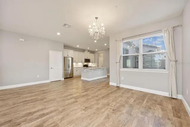 a view of an empty room with kitchen and window