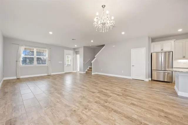 a view of empty room with wooden floor and kitchen