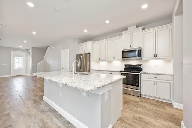 a kitchen with stainless steel appliances granite countertop a sink stove and refrigerator