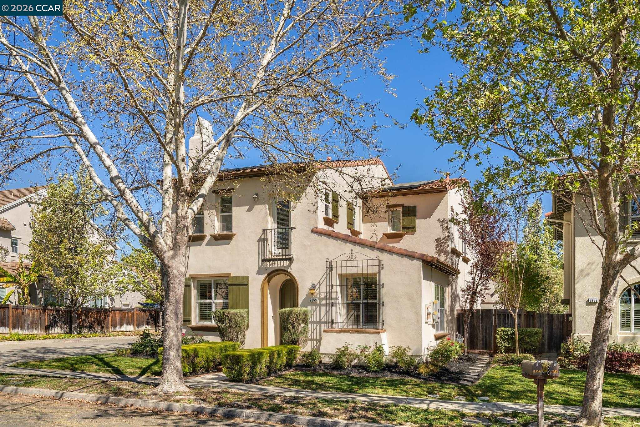 a view of a white house with a large tree