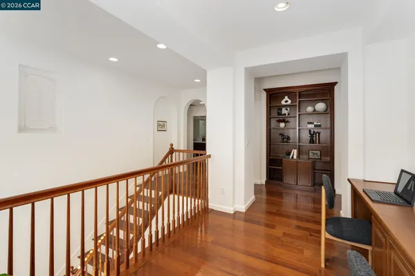 a view of a hallway with wooden floor and furniture