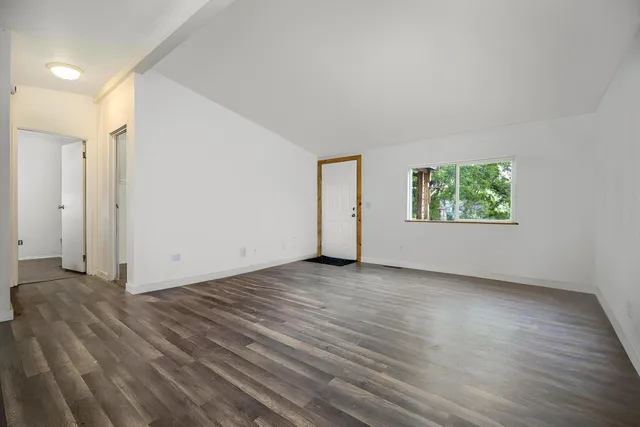 an empty room with wooden floor windows and closet