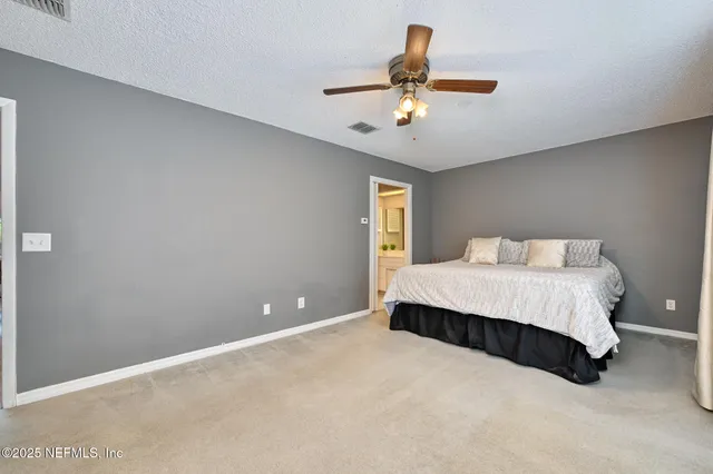 a spacious bedroom with a bed and a ceiling fan
