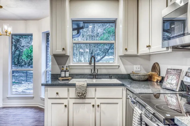a kitchen with kitchen island granite countertop a sink and a white wooden cabinets