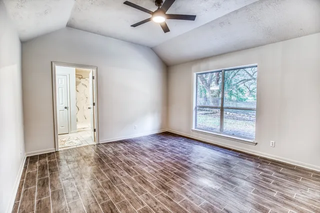 an empty room with wooden floor chandelier fan and windows