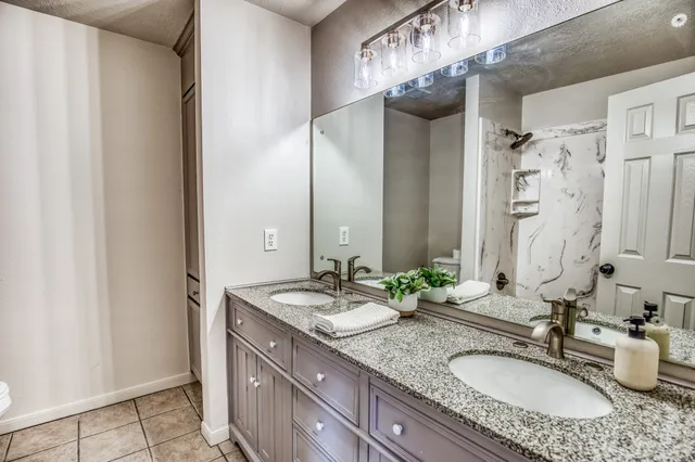 a bathroom with a granite countertop double vanity sink and mirror