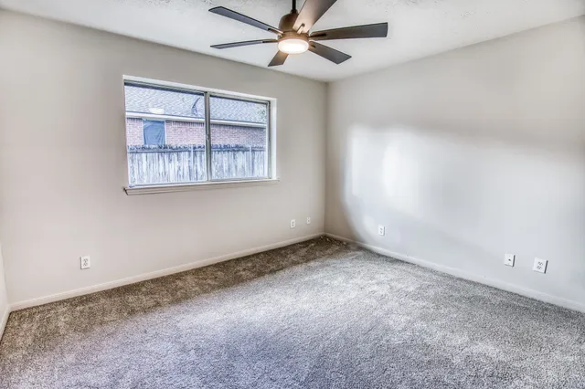 an empty room with a window and a fan
