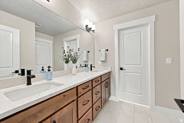 754 West 400 North Mapleton, UT 84664 - Photo 48 of 86 Extra large bathroom. Dual vanity with an integrated rectangular sink, white stone-finish countertop, dark wood-finish cabinetry, and black hardware.