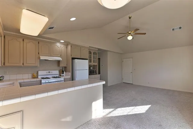 a view of a kitchen with a sink and dishwasher a refrigerator with wooden floor
