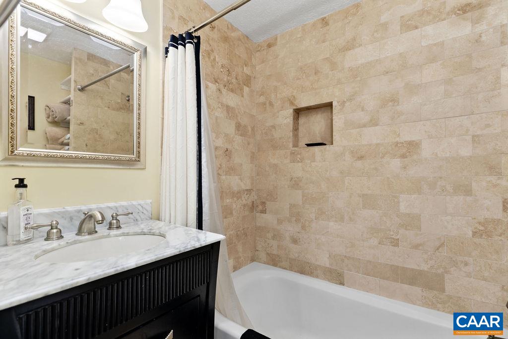 411 Three Ridges Roseland, VA 22967 - Photo 15 of 27 a bathroom with a granite countertop sink a mirror a bathtub and shower