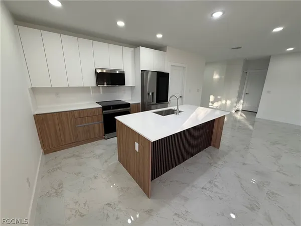 a kitchen with kitchen island sink refrigerator and white cabinets