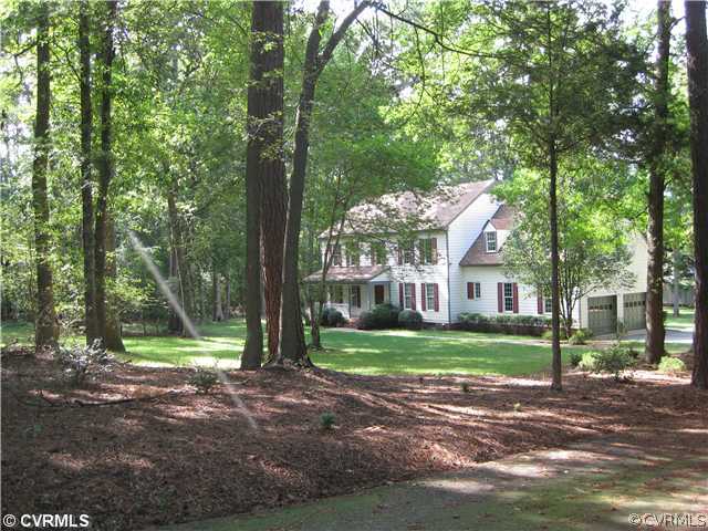 a view of a house next to a yard with big trees