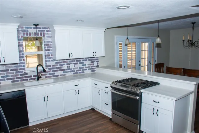 a kitchen with granite countertop stainless steel appliances a sink stove and cabinets