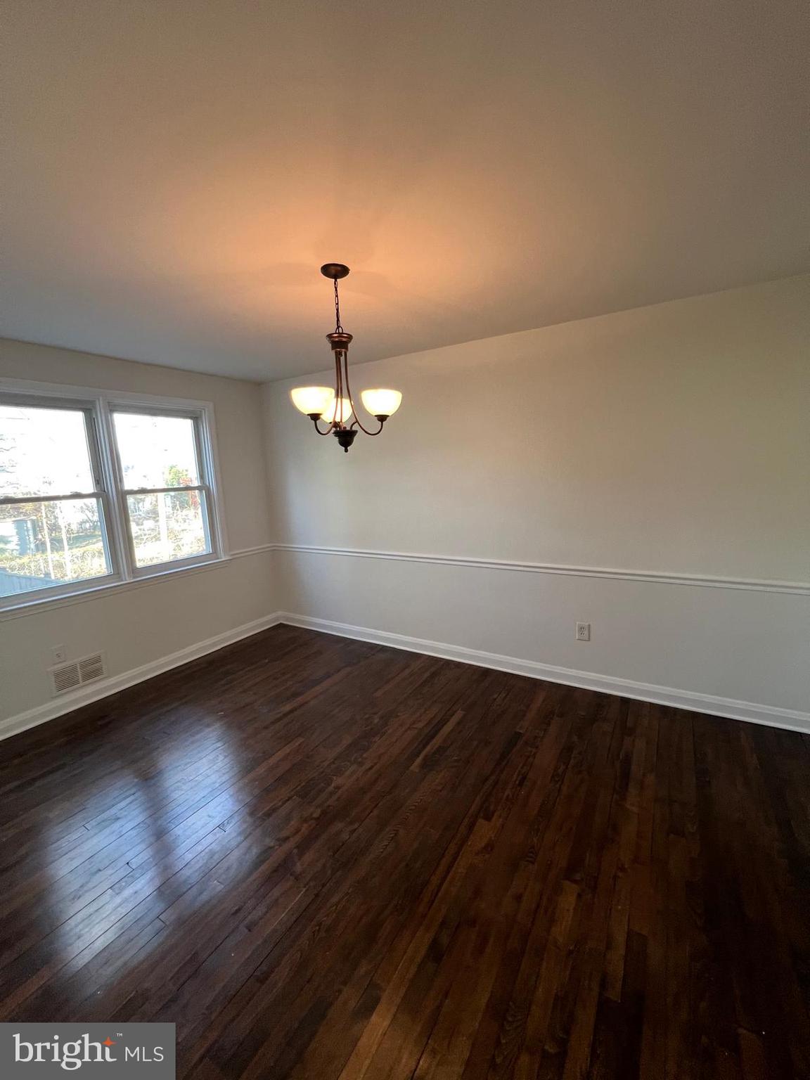 603 Braeside Road Baltimore, MD 21229 - Photo 27 of 30 an empty room with wooden floor chandelier and windows