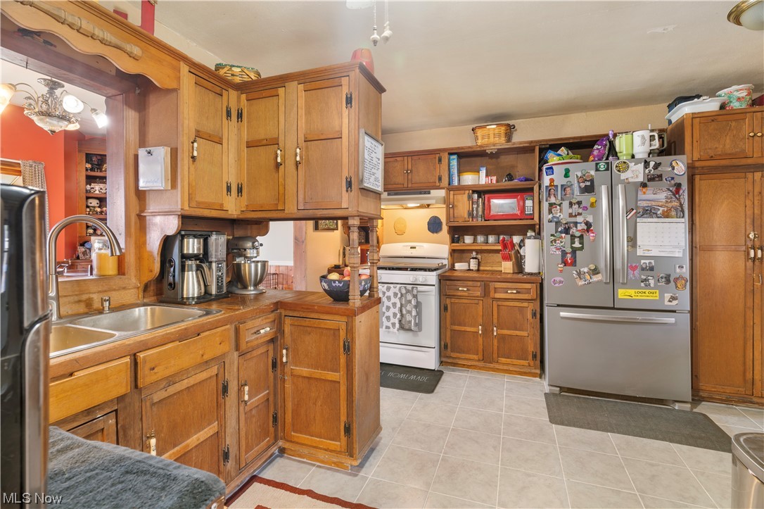 4815 Ridge Avenue Southeast Canton, OH 44707 - Photo 10 of 28 Kitchen with stainless steel fridge, light tile flooring, brown cabinets, and white range