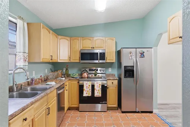 a kitchen with stainless steel appliances granite countertop a refrigerator a stove and a sink