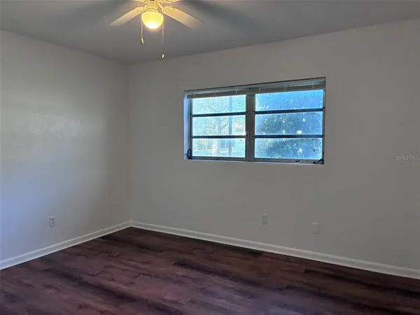 a view of an empty room with wooden floor and a window