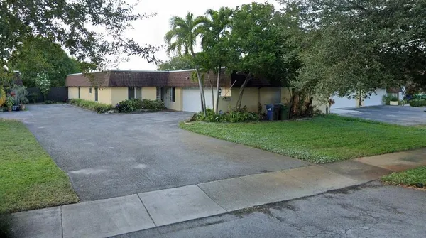 a front view of a house with a garden and trees