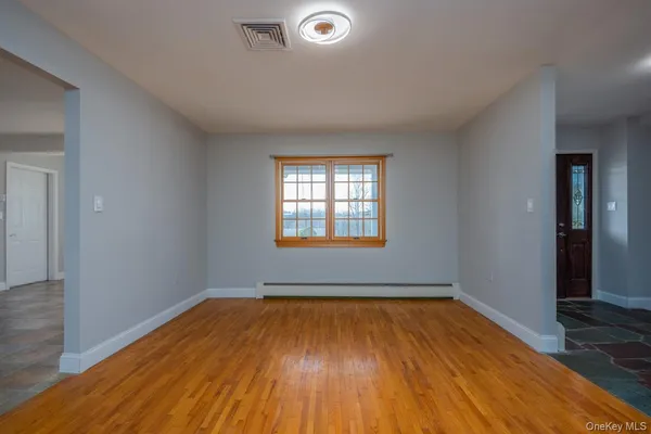 an empty room with wooden floor and windows