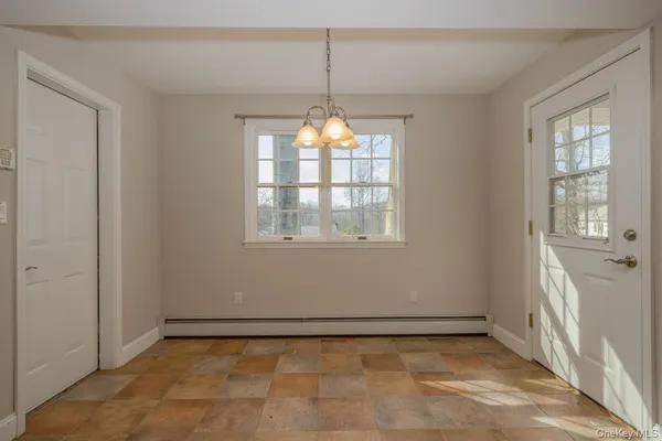 an empty room that has a chandelier fan and windows