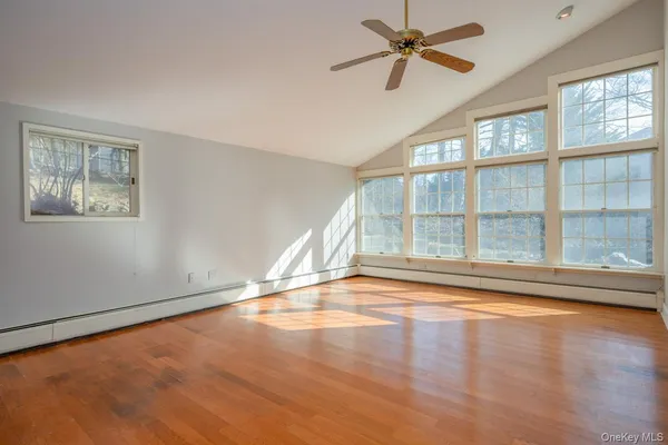 a view of empty room with wooden floor and fan