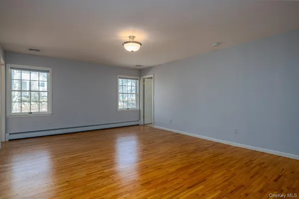 a view of an empty room with wooden floor and window
