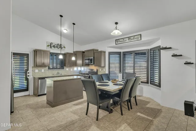 a kitchen with stainless steel appliances granite countertop a stove top oven a sink dishwasher a dining table and chairs with wooden floor