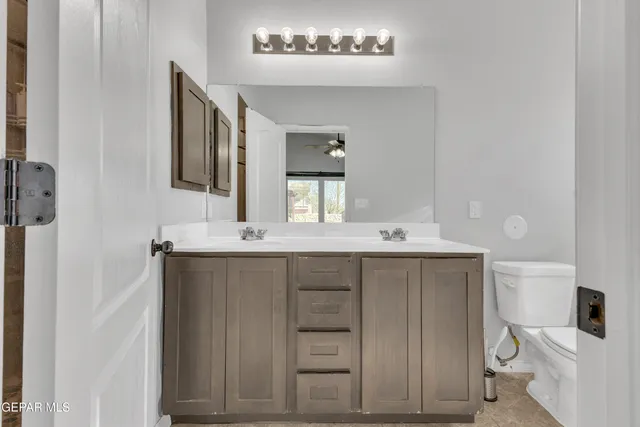 a bathroom with a granite countertop bathtub sink vanity mirror and toilet