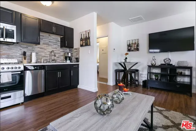 a living room with stainless steel appliances furniture and a flat screen tv