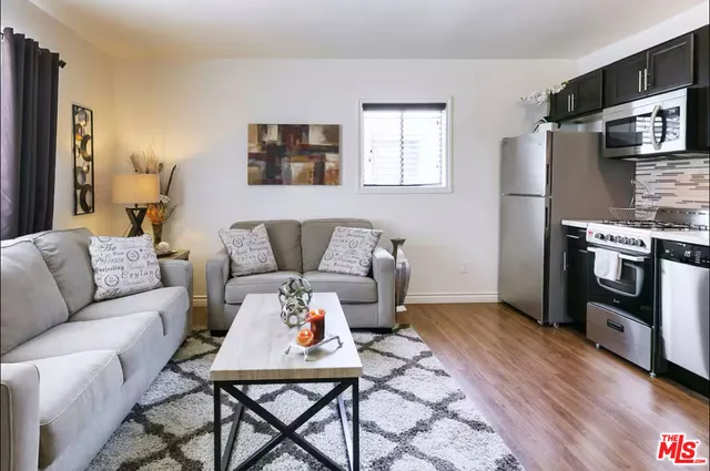 a living room with furniture a flat screen tv and a refrigerator