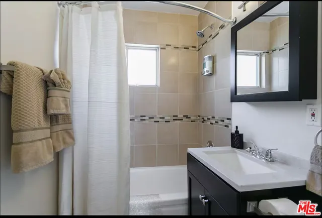 a bathroom with a sink and mirror with bathtub