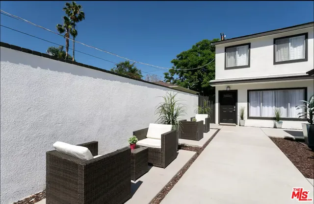 a view of a patio with couches table and chairs and potted plants