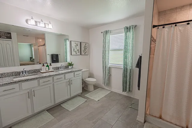 a spacious bathroom with a double vanity sink a mirror and a shower