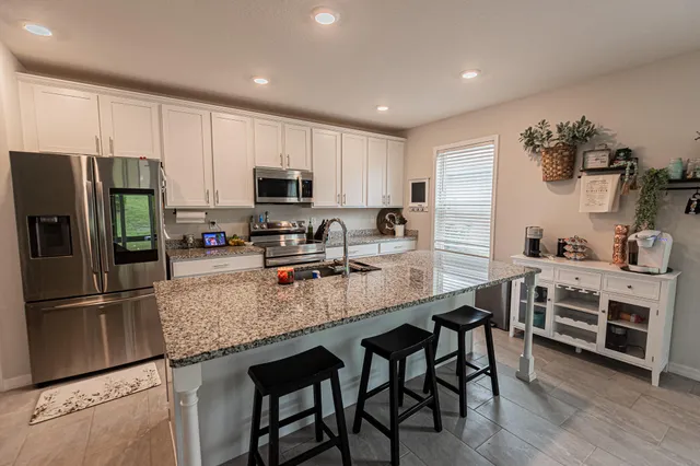 a kitchen with kitchen island granite countertop a table chairs microwave and refrigerator