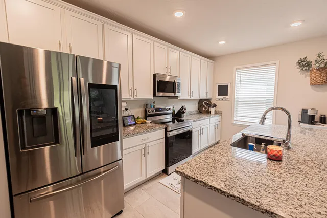 a kitchen with stainless steel appliances granite countertop a refrigerator stove and sink