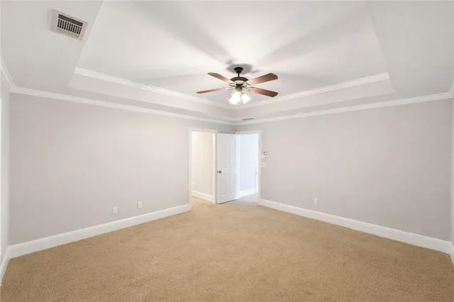 an empty room with chandelier fan and windows