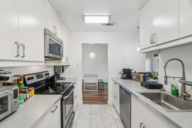 a kitchen with stainless steel appliances a stove a sink and a microwave