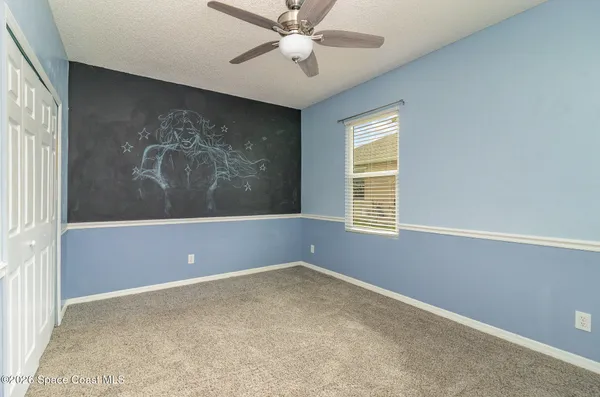 an empty room with windows and fan