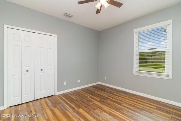 a view of empty room with wooden floor and fan