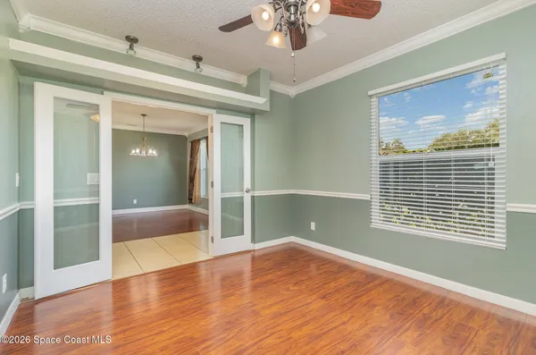 a view of empty room with wooden floor and fan