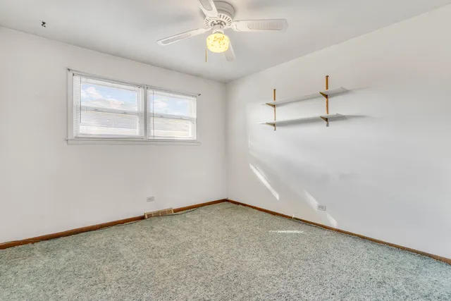 an empty room with a window and ceiling fan
