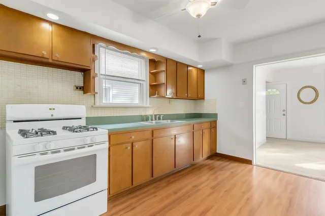 a kitchen with granite countertop a stove a sink and dishwasher with white cabinets