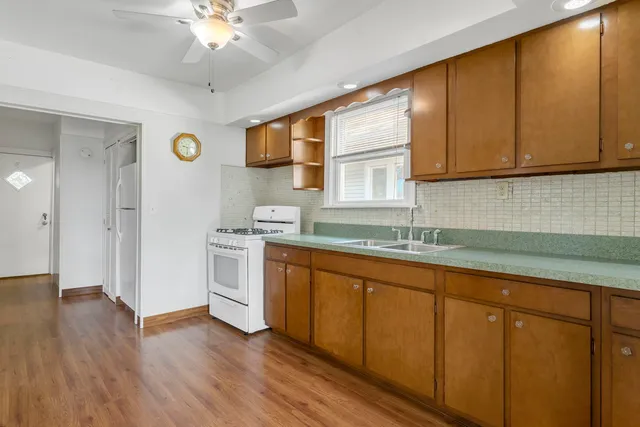 a kitchen with stainless steel appliances granite countertop a sink a stove cabinets and wooden floor
