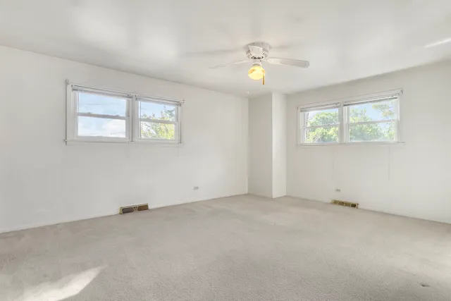 an empty room with windows and fan