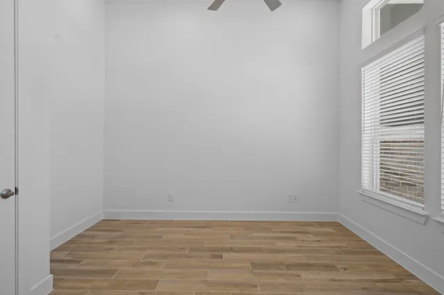 a view of an empty room with wooden floor and a window